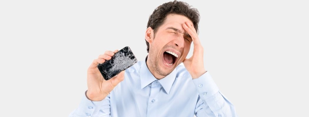 cellphone repair and exchange man with iphone cracked screen a man in agony, absolutely beside himself, holding a broken iphone with a cracked screen