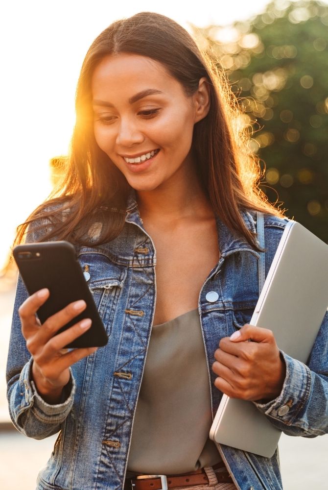 A smiling woman looking at her repaired iPhone with cracked screen fixed